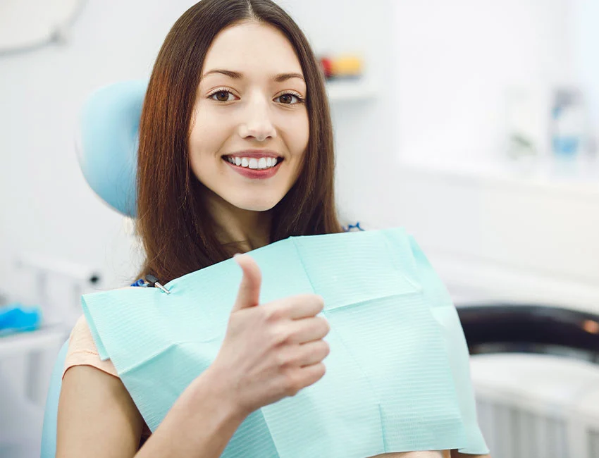 Female patient thumbs up after dental treatment