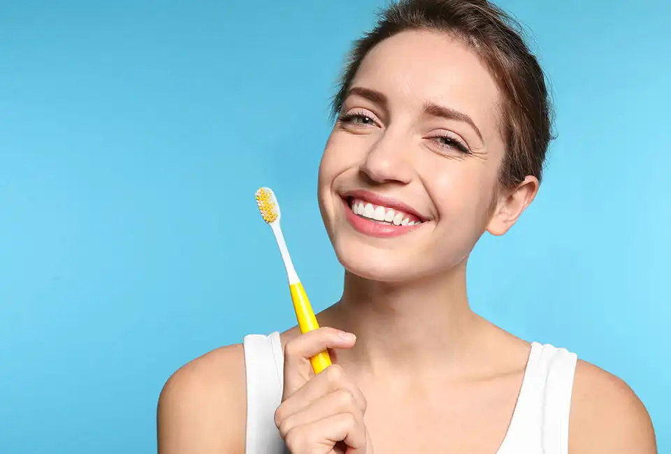 Patient holding tooth brush and smiling in Canyon Country, CA